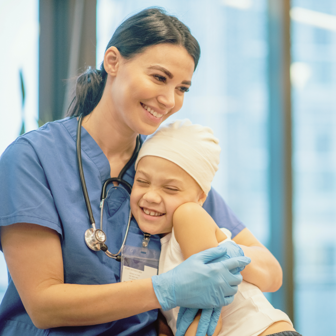 A female nurse hugging a young girl. They're both smiling and laughing.