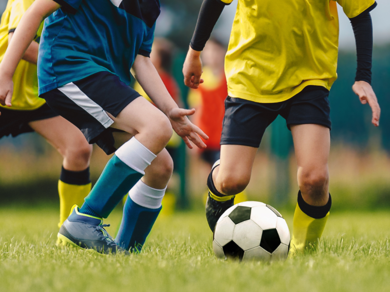 kids playing a game of competitive football. Two boys are running at the soccer ball.